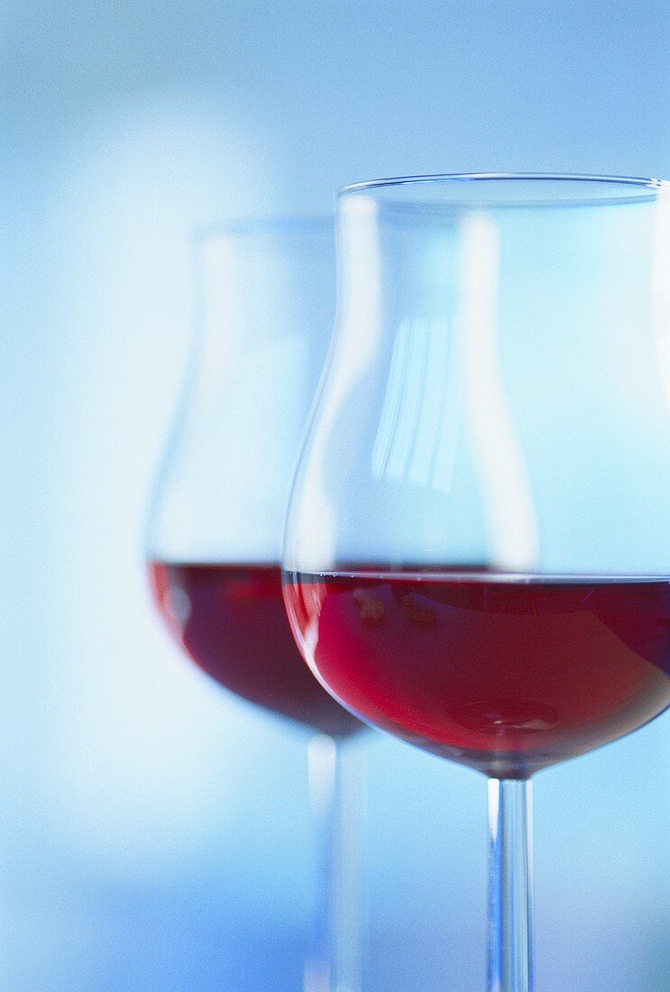 Two glasses of red wine against blue backdrop