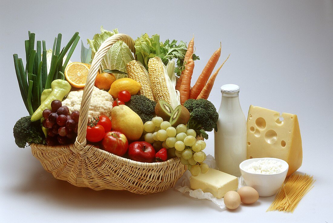 Basket of fruit & vegetables, dairy products, eggs beside it