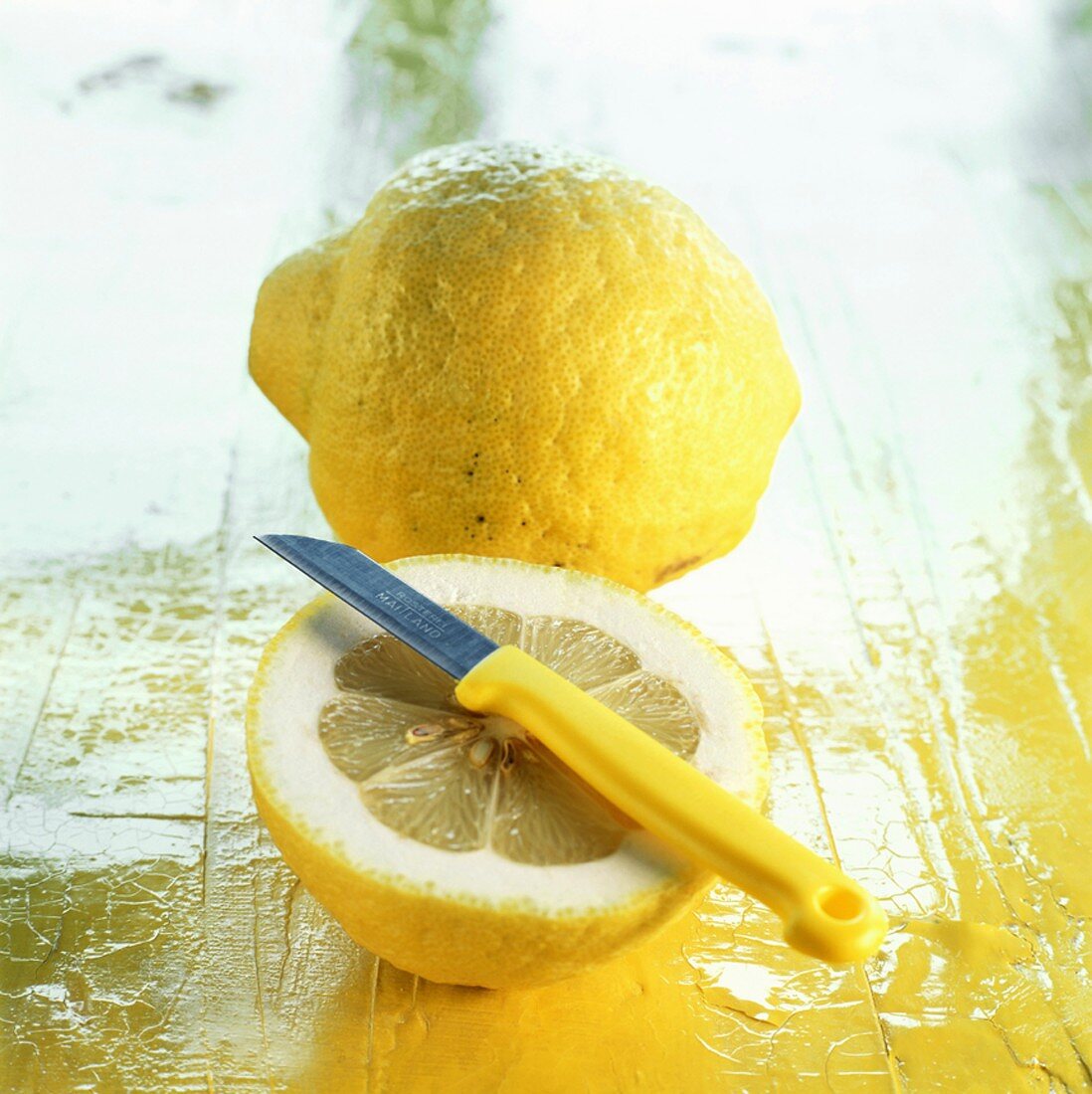 Eine ganze und eine halbe Zitrone mit Messer