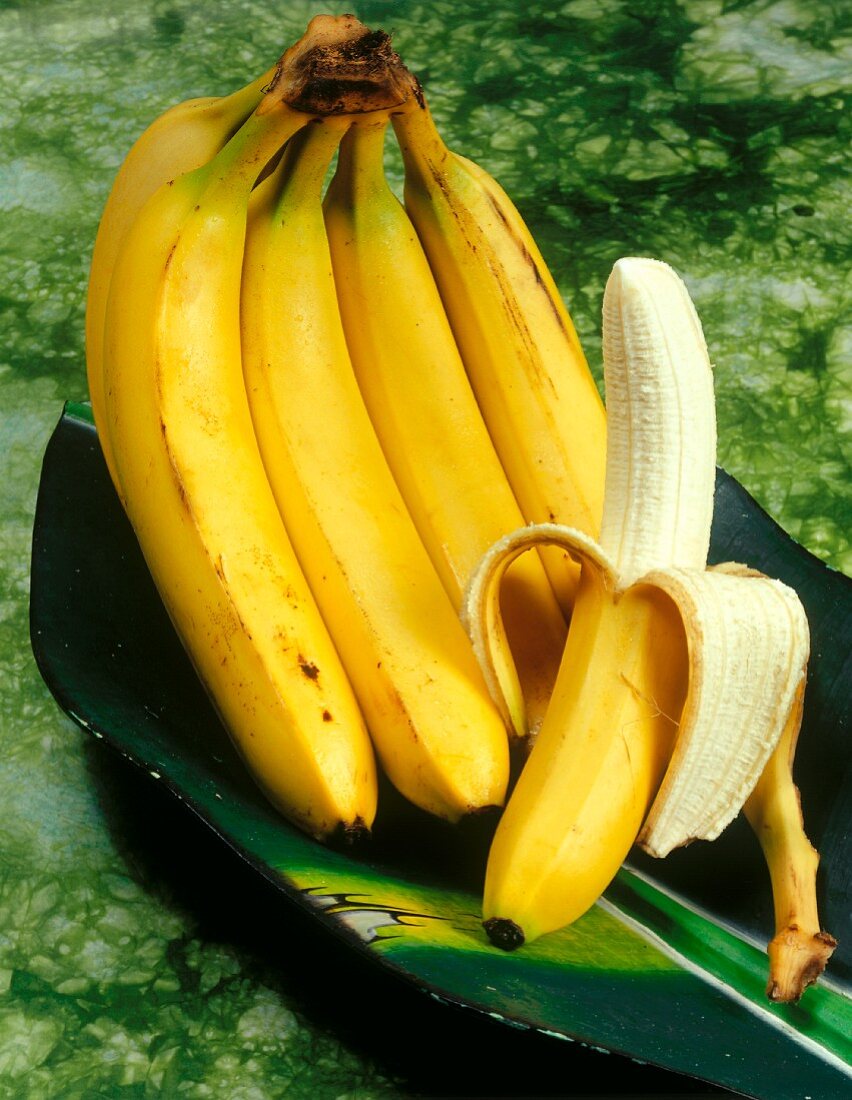 A bunch of bananas and a half-peeled banana