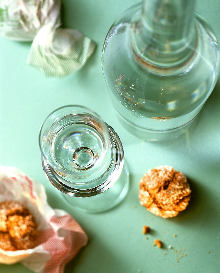 Ein Glas und eine Flasche Grappa mit Mandelgebäck (von oben)