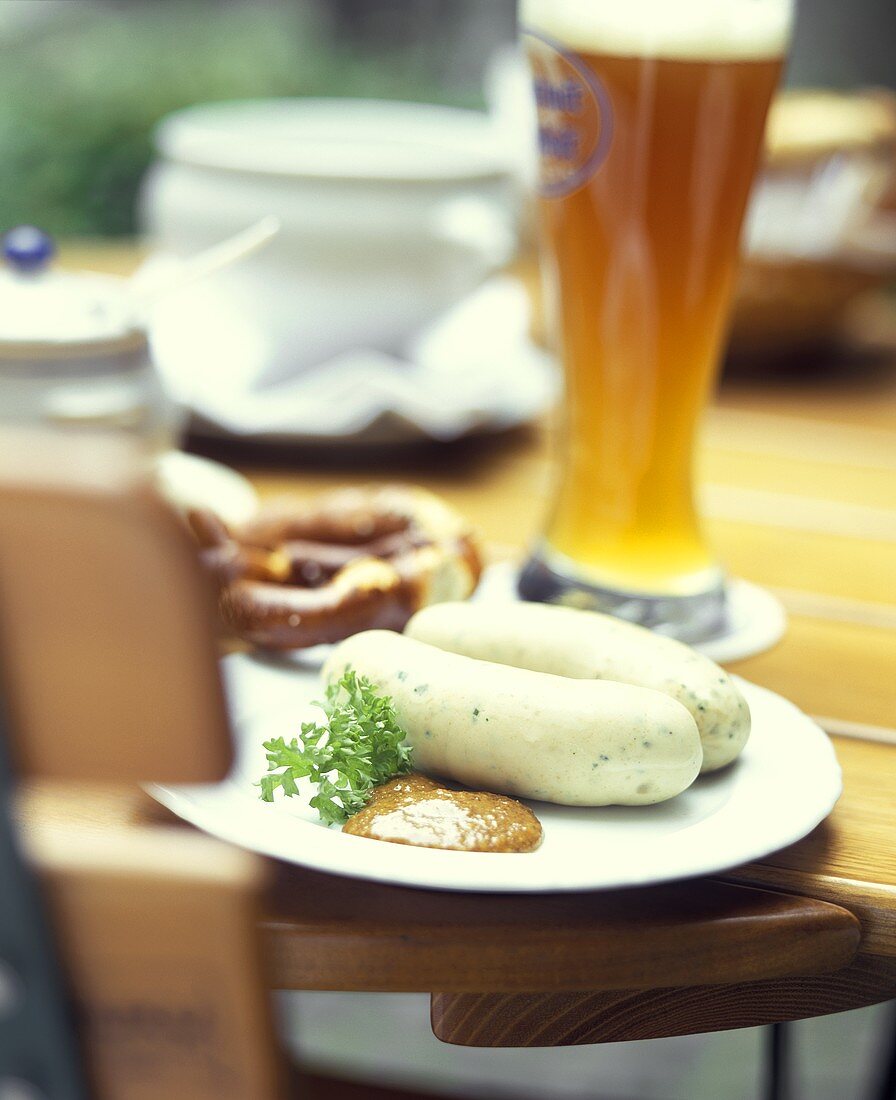 Weisswurst mit Brezel und Weissbier auf Biergartentisch