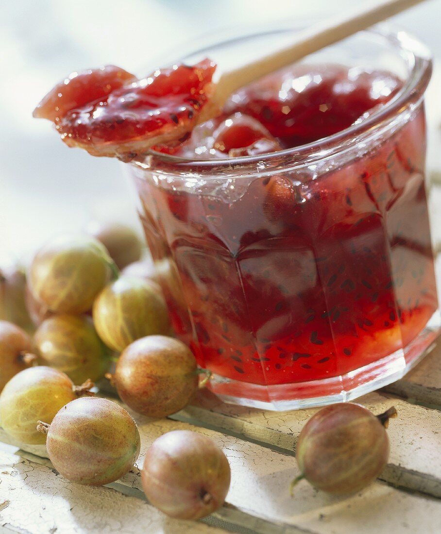 Gooseberry jam in jar and on wooden spoon