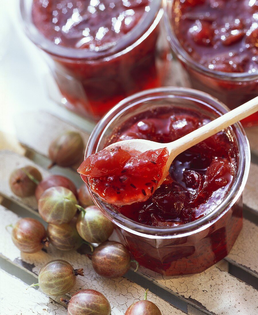 Gooseberry jam in a jar and on a wooden spoon
