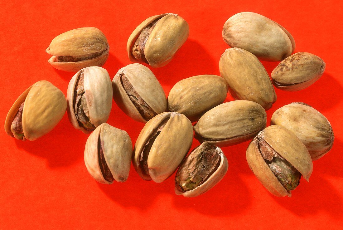Salted pistachios on red background