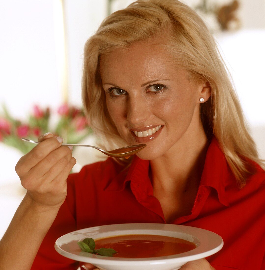 Frau hält ein Teller mit Tomatensuppe