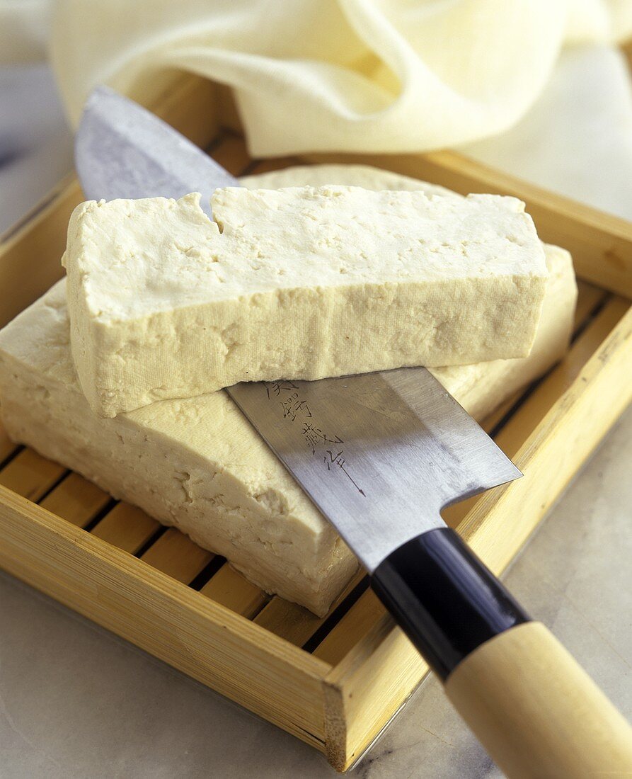 Tofu mit asiatischem Messer auf Holzkästchen