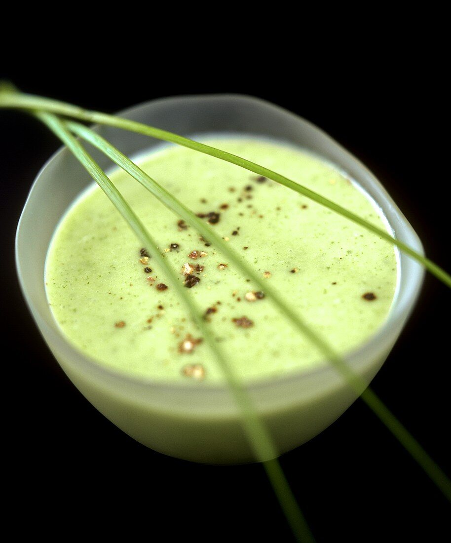 Erbsencremesuppe, garniert mit Pfeffer und Schnittlauch