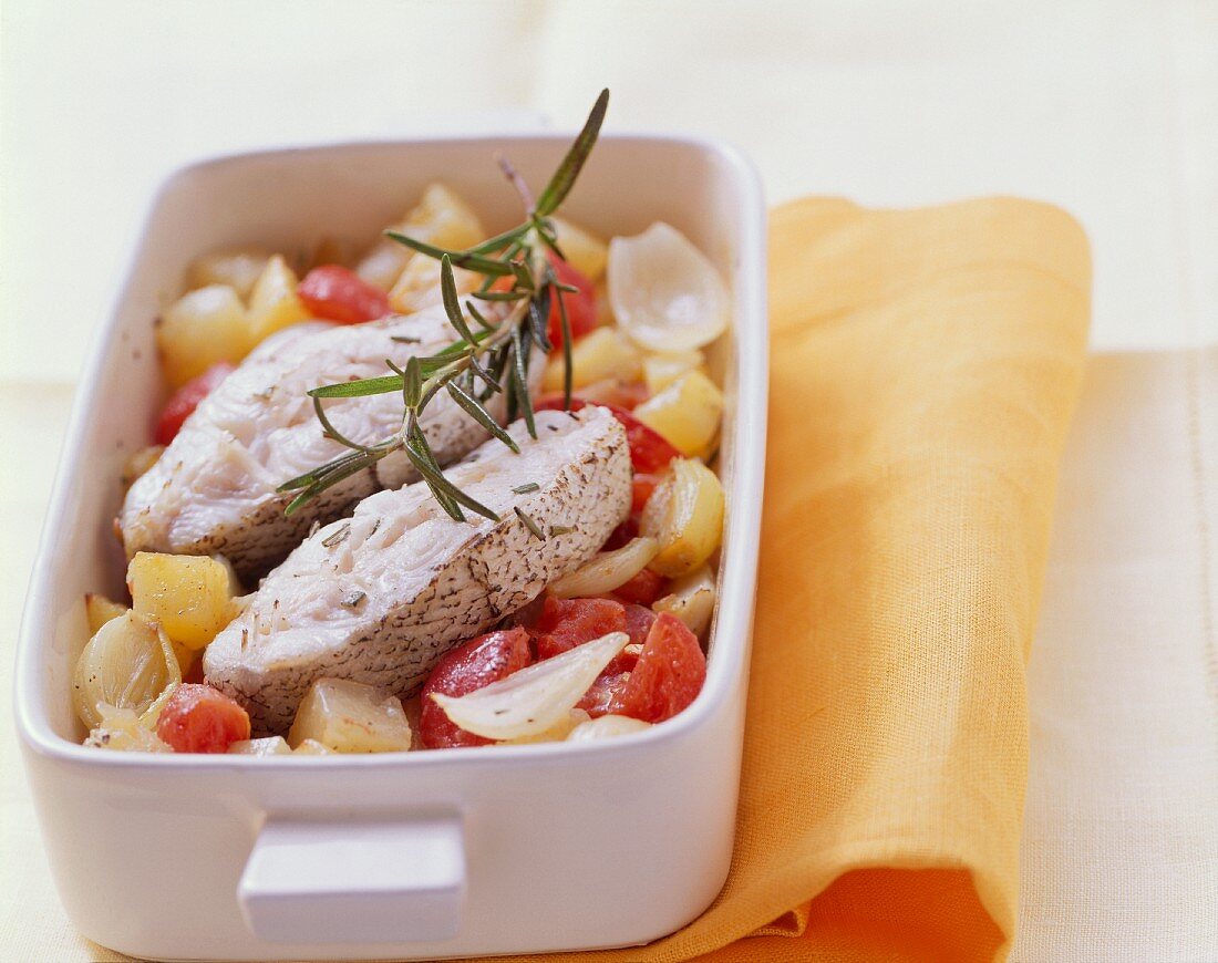 Haddock cutlets on bed of vegetables in baking dish