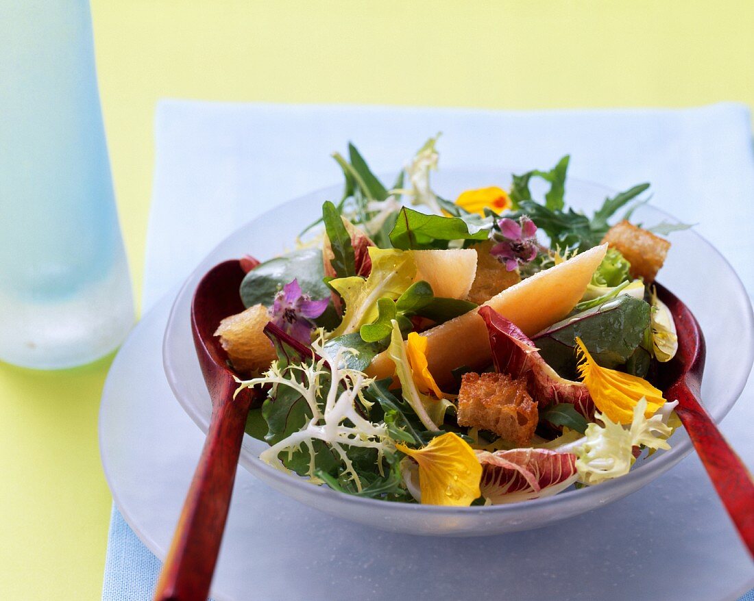 Gemischter Blattsalat mit Blüten, Melonenstücken und Croûtons