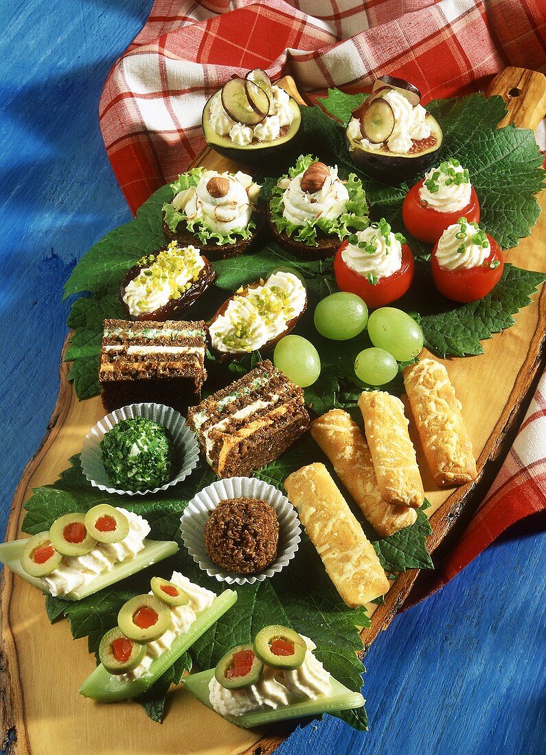 Assorted snacks with cream cheese on a wooden board