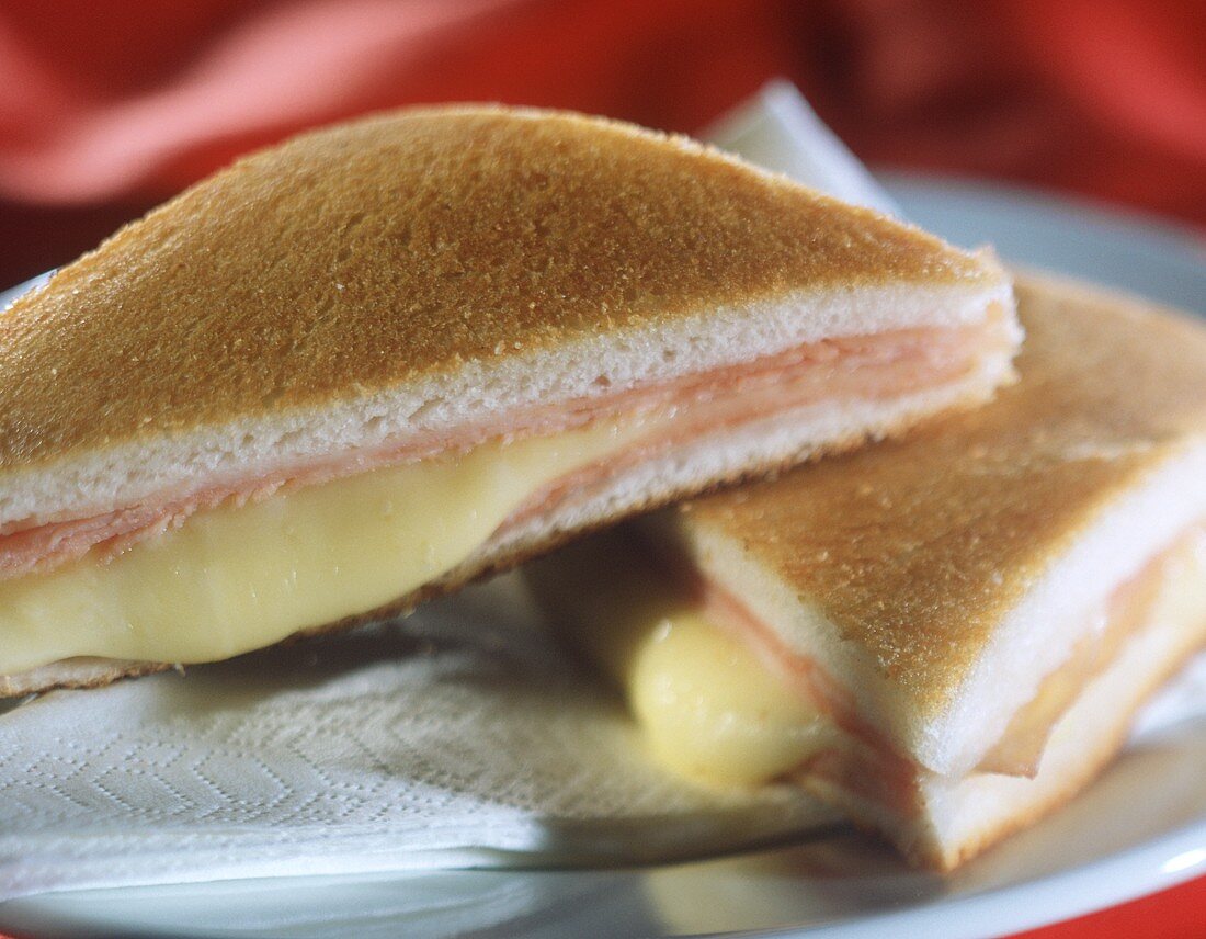 Two tramezzini with cheese and ham filling, toasted