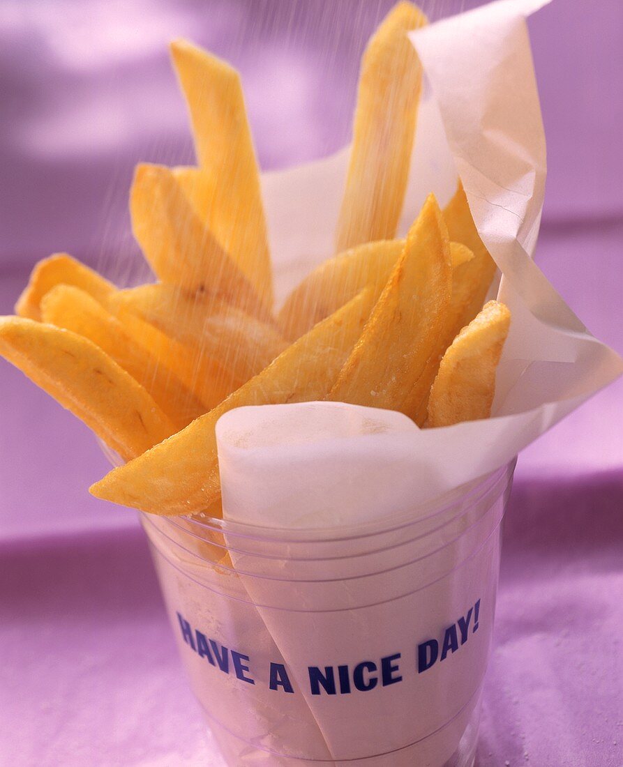 Chips in a plastic container being sprinkled with salt