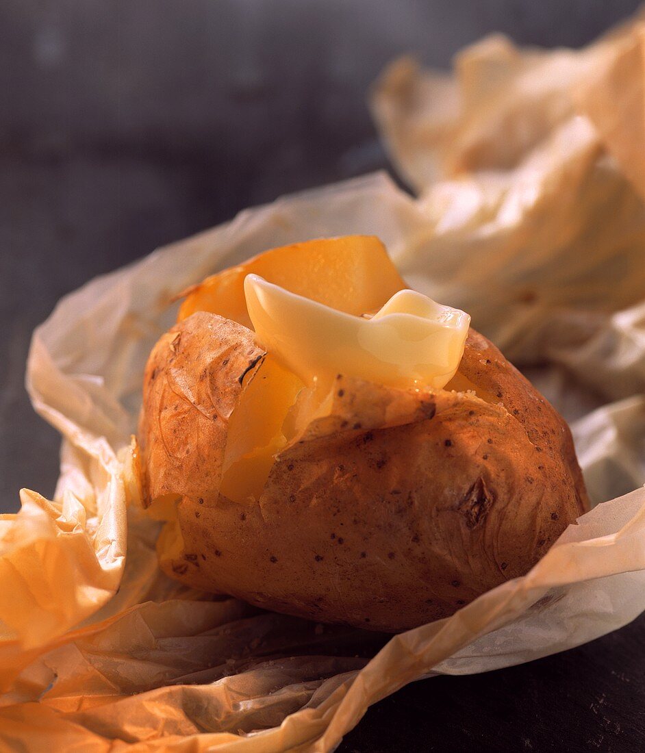 Baked potato with melting butter on baking paper