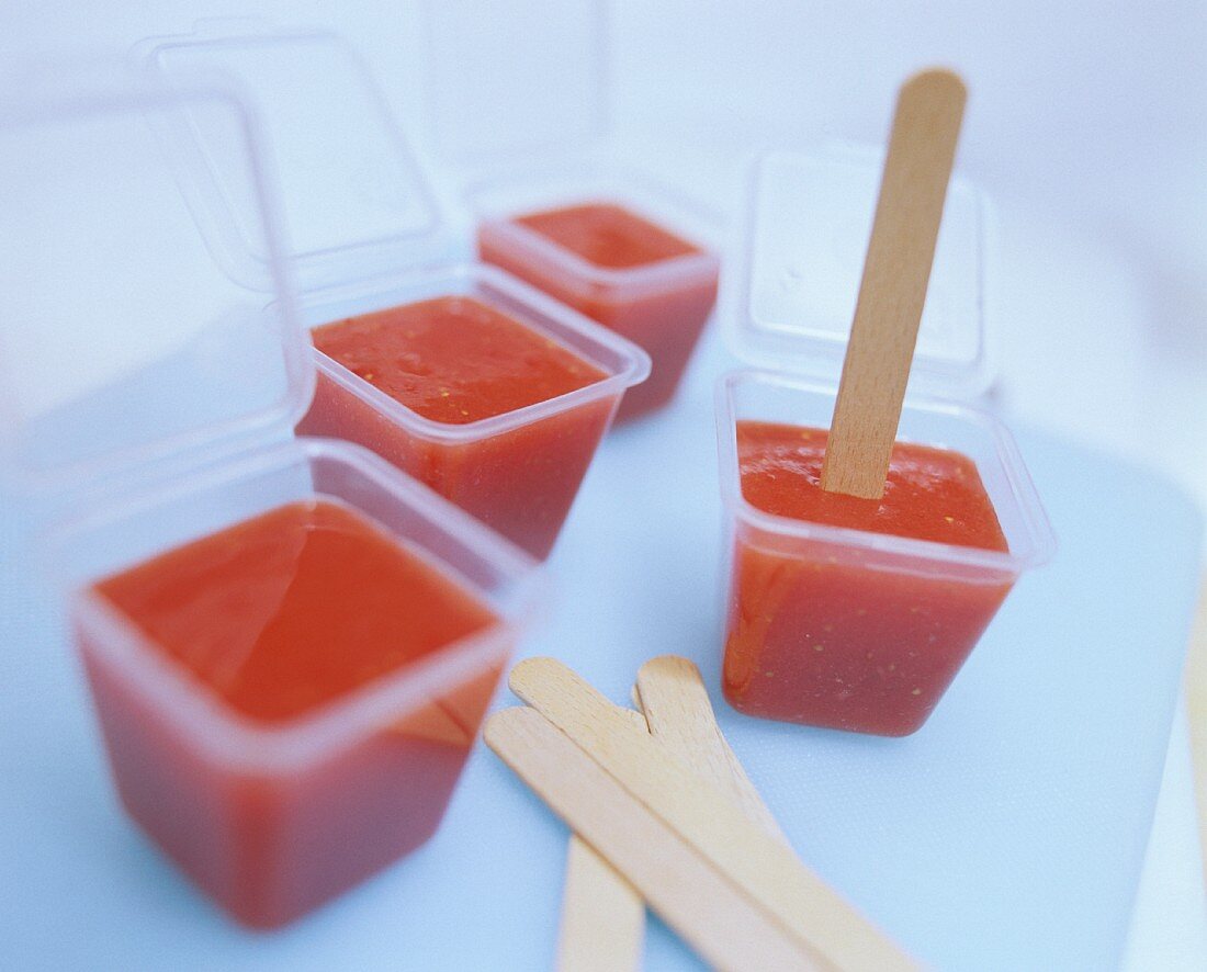 Frozen strawberry puree with sticks in ice cube maker