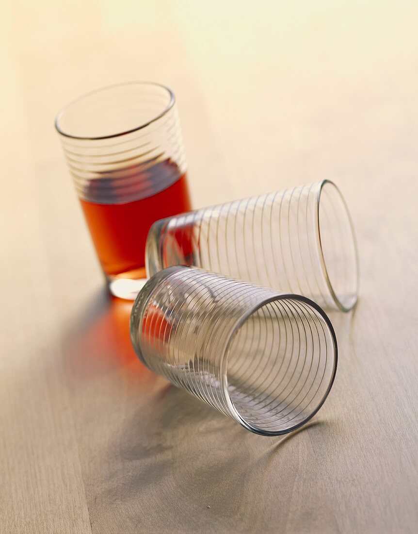 Ein Glas Kirschsaft, davor zwei leere Gläser