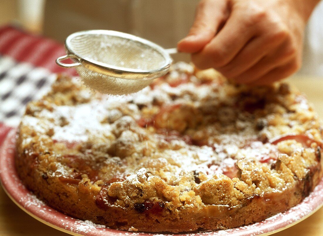 Johannisbeer-Pfirsich-Kuchen mit Puderzucker bestäuben