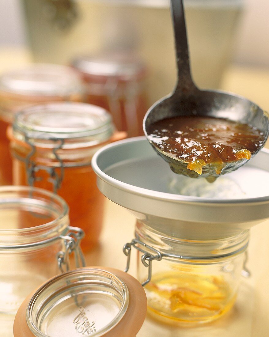 Pouring orange marmalade into jars
