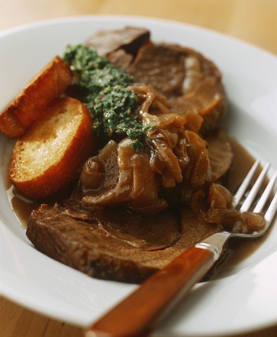 Braised steak with onions with green sauce and toasted bread
