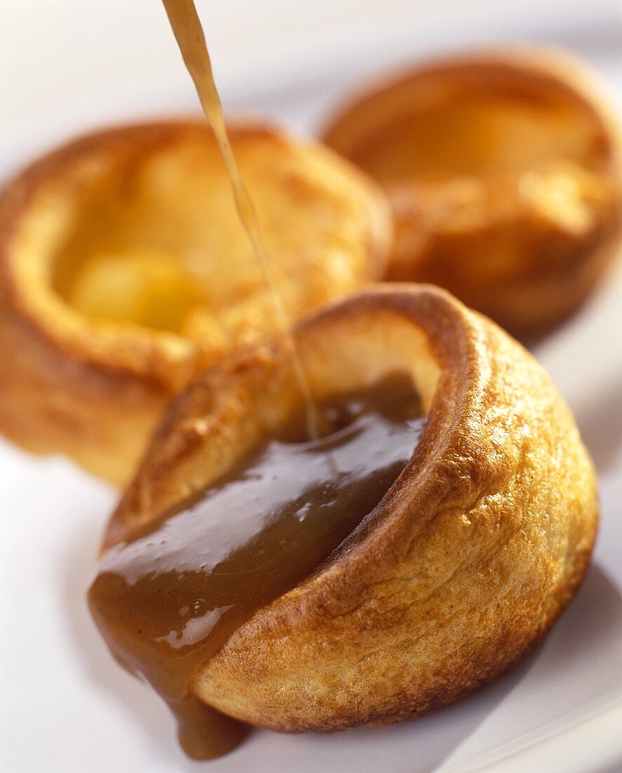 Fruit sauce being poured over Yorkshire pudding