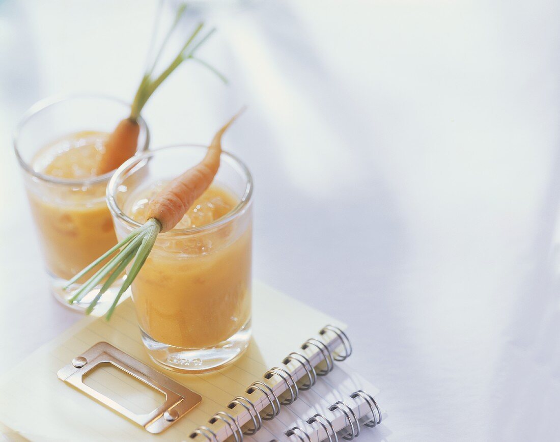 Banana and carrot drink in two glasses on exercise books