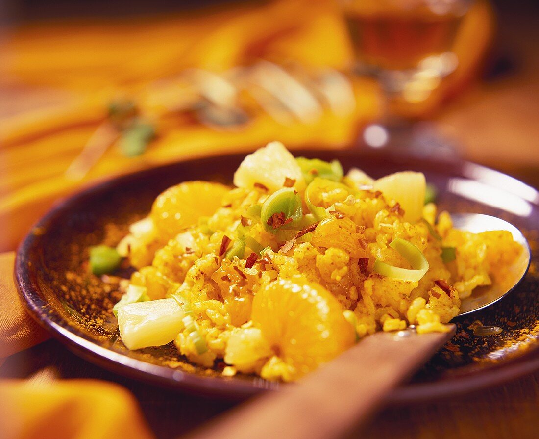 Spicy curry rice salad with orange segments, pineapple & leek