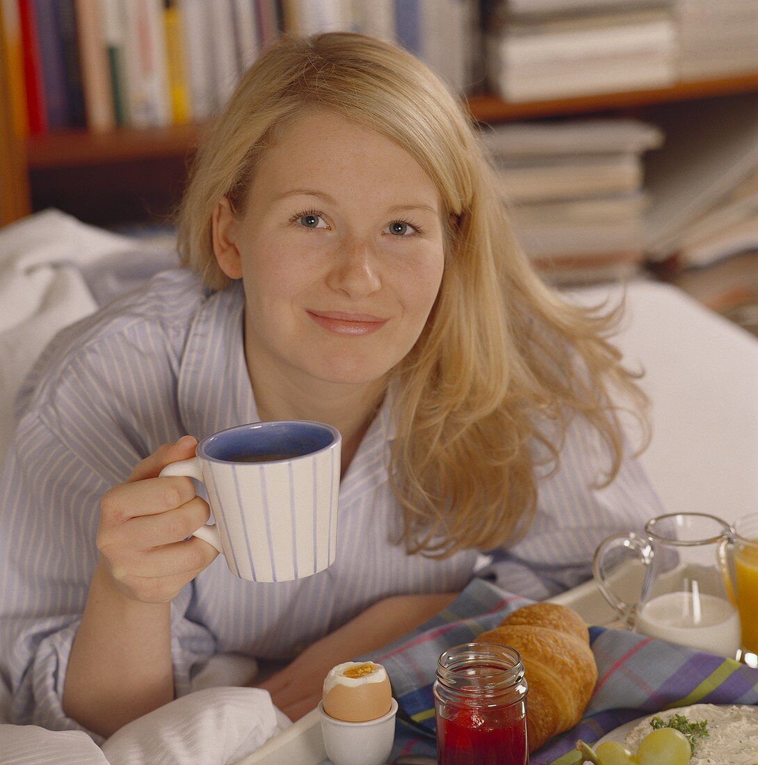 Breakfast in bed: woman with coffee cup and breakfast tray