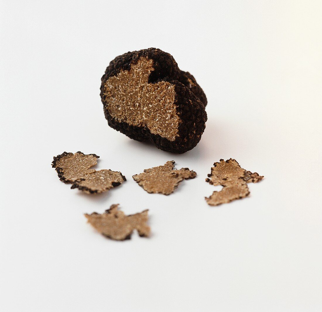 Black truffle with a slice cut and truffle curls