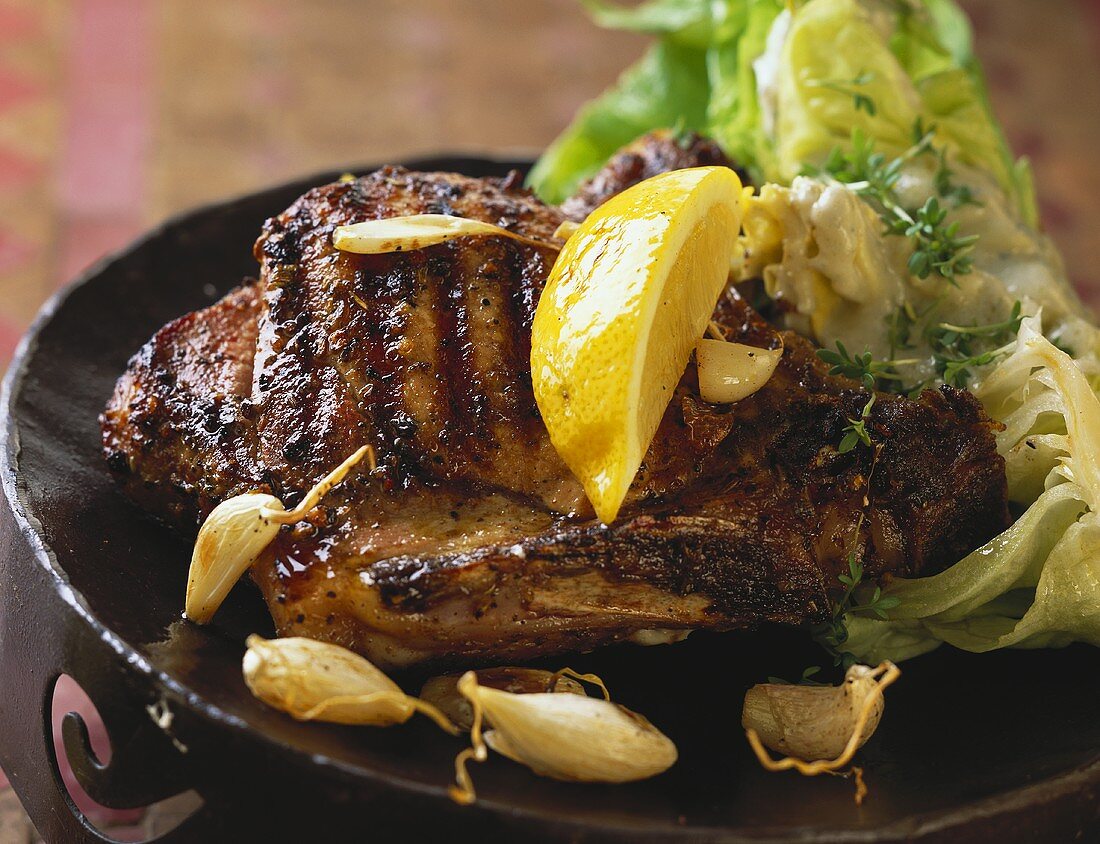 Barbecued pork chop with garlic and wedge of lemon