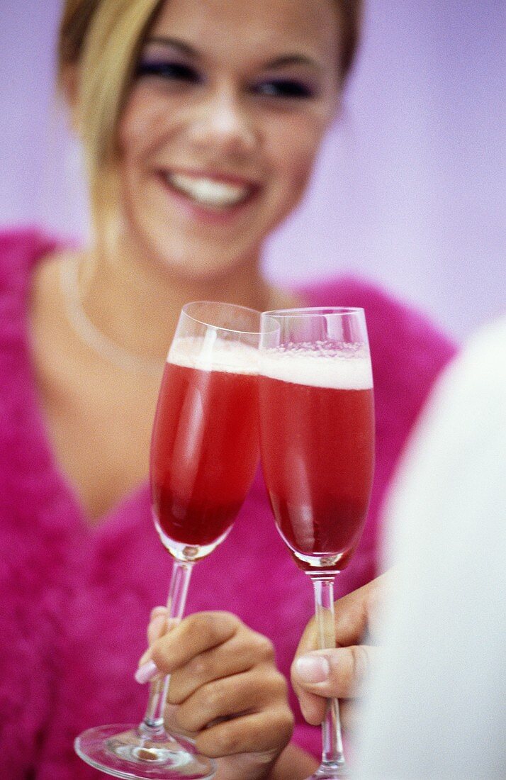 Junge Frau beim Anstossen mit Cocktail 'Prosecco Red'