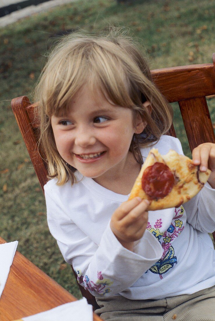 Mädchen isst Pizza im Freien