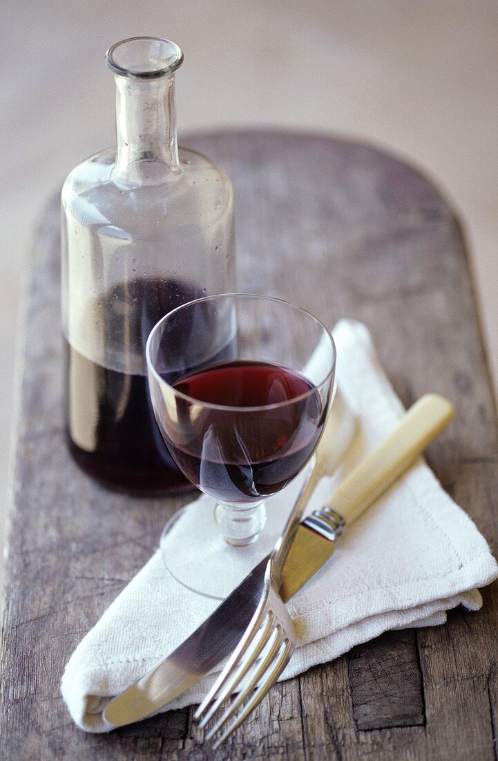 Stillleben mit Rotweinglas, Weinkaraffe, Serviette & Besteck