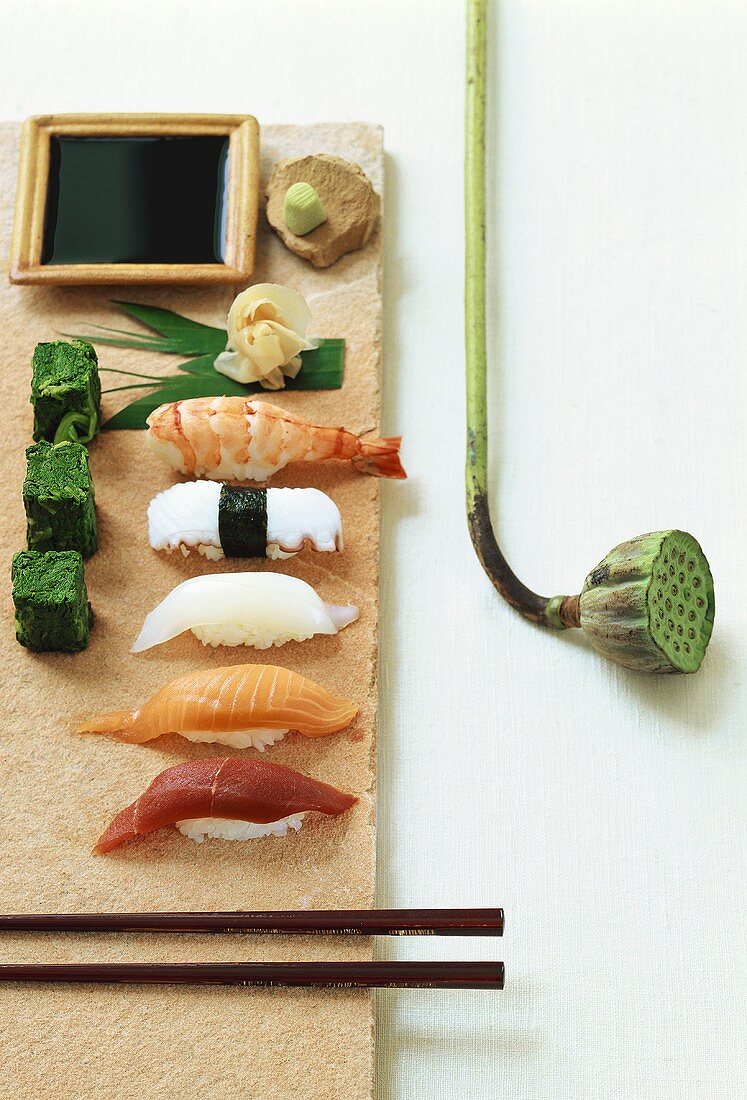 Various Nigiri sushi, pastes, soy sauce and lotus capsule