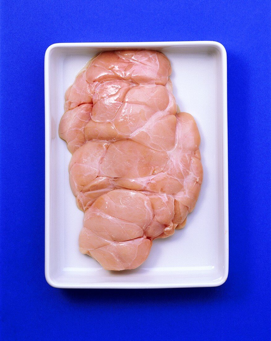 Veal sweetbread in white bowl on blue background