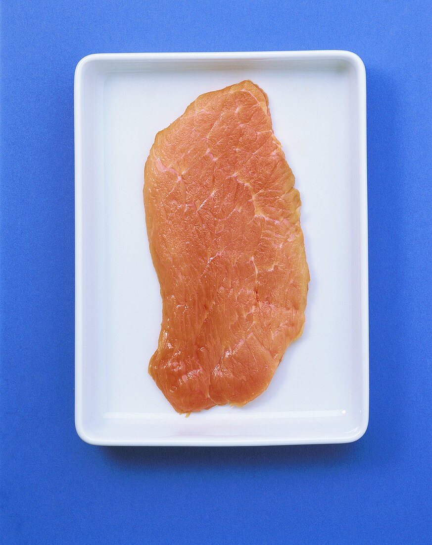 Veal escalope in white bowl on blue background