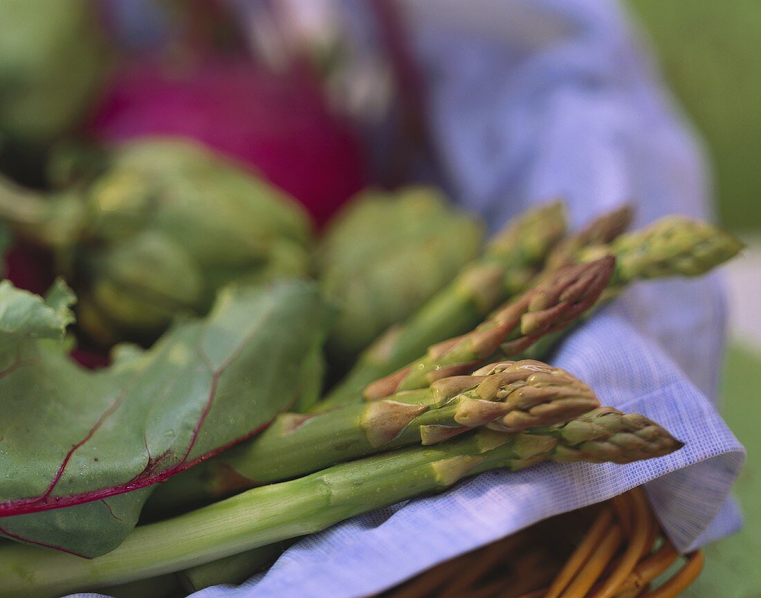 Stillleben mit grünem Spargel und Gemüse im Korb