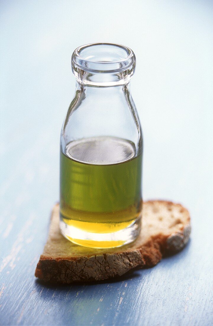Olivenöl in kleiner Flasche und eine Brotscheibe