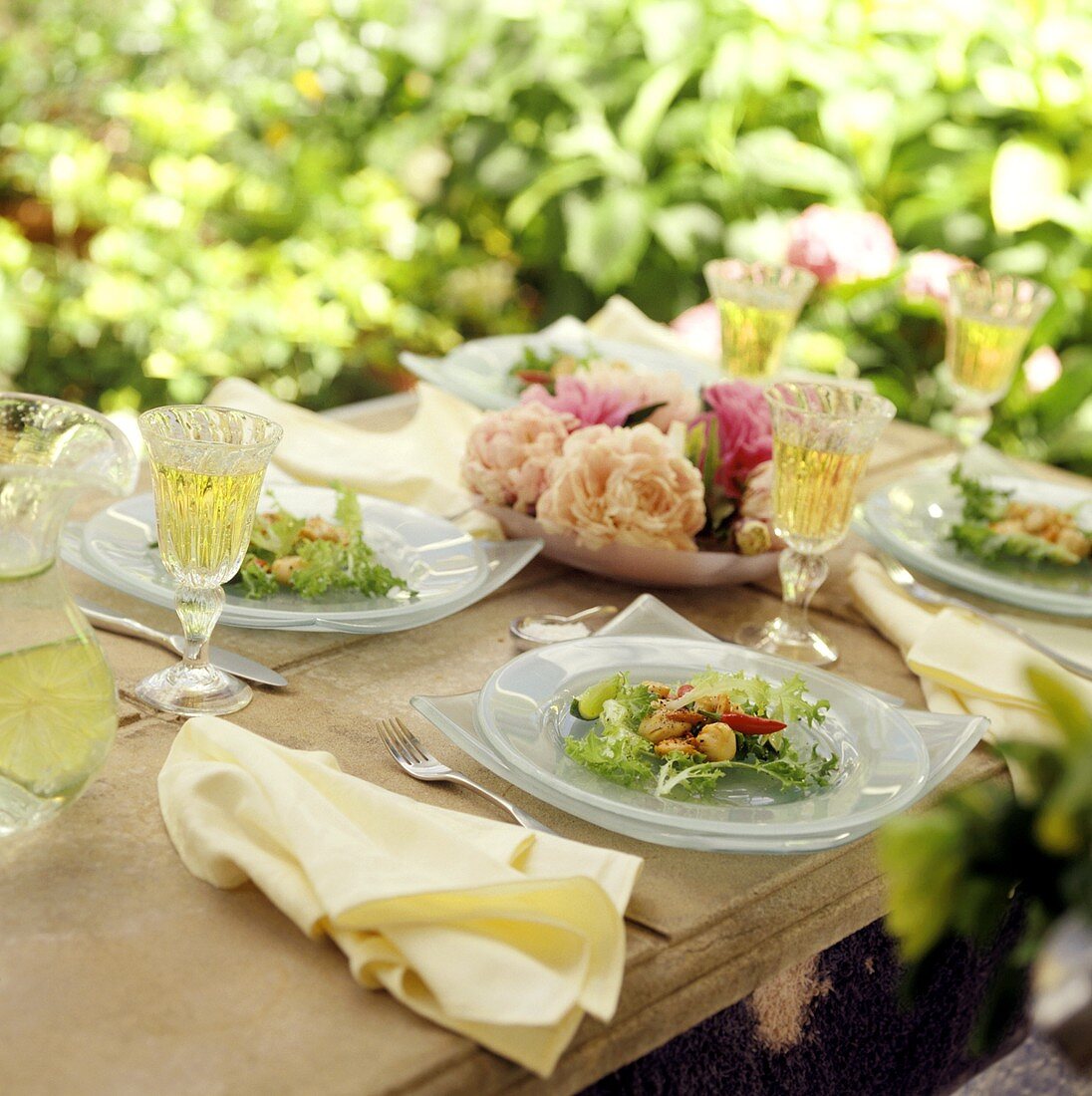 Gedeckter Tisch mit Wein und Jacobsmuscheln auf Salatteller