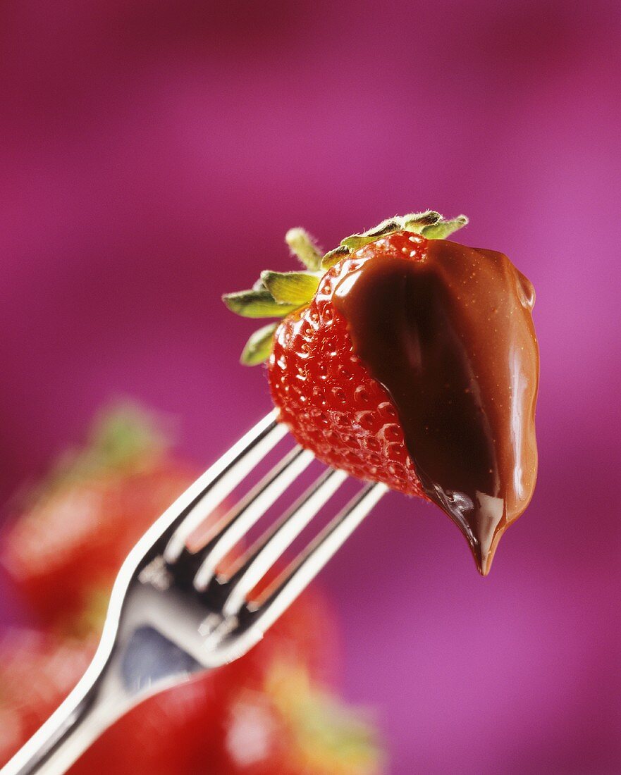 Eine Erdbeere mit Schokoladenüberzug auf einer Gabel