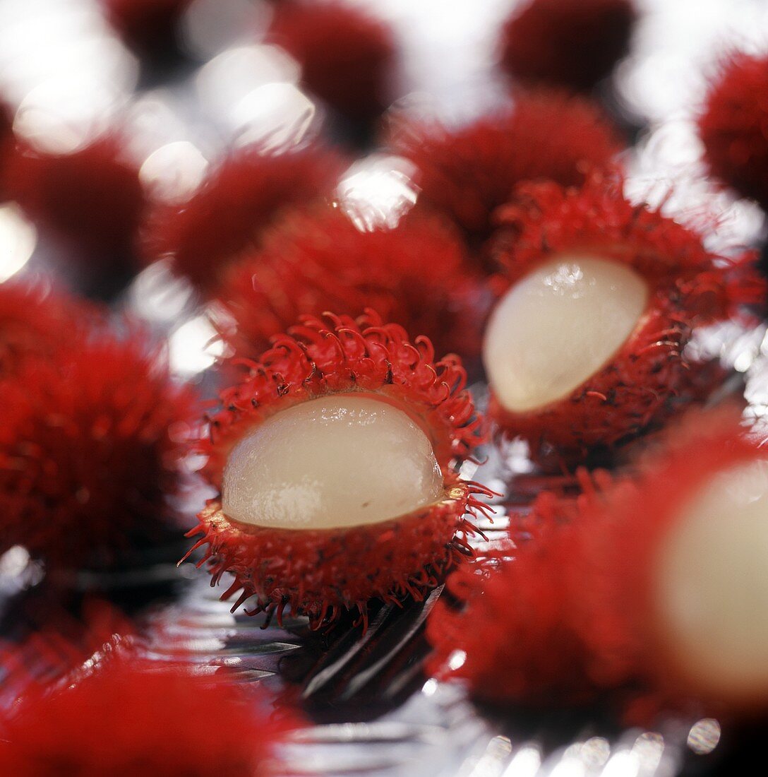 Lychees, two opened, on sheet of glass