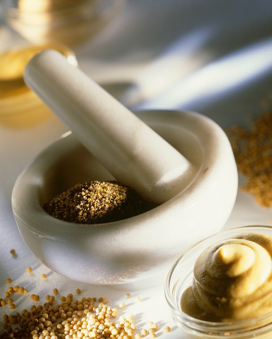 Mortar with mustard seeds, bowl of mustard beside it