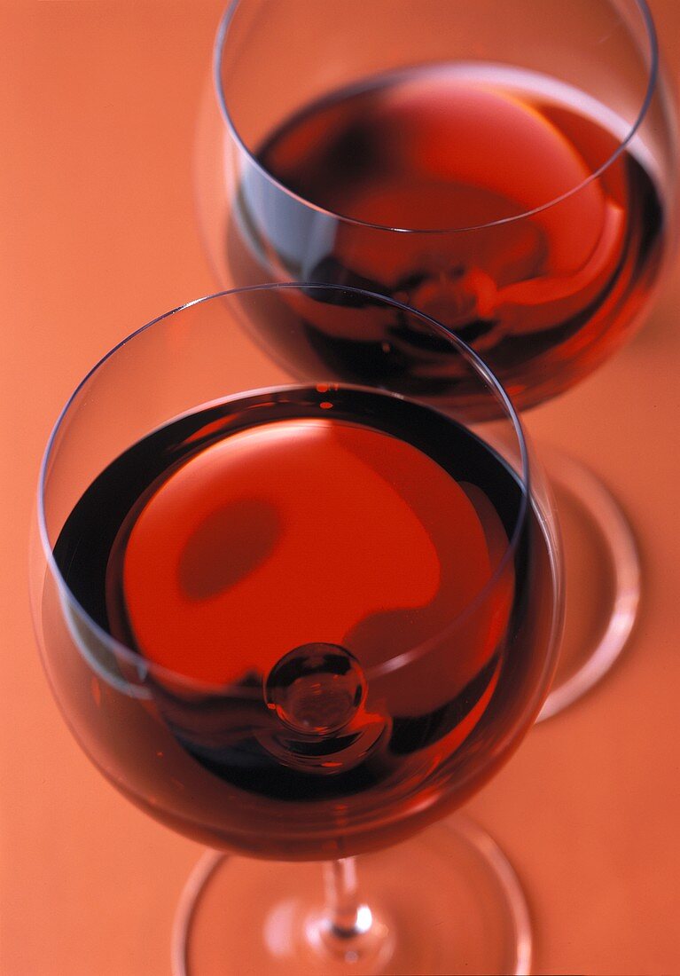 Zwei Gläser Rotwein auf rotem Untergrund