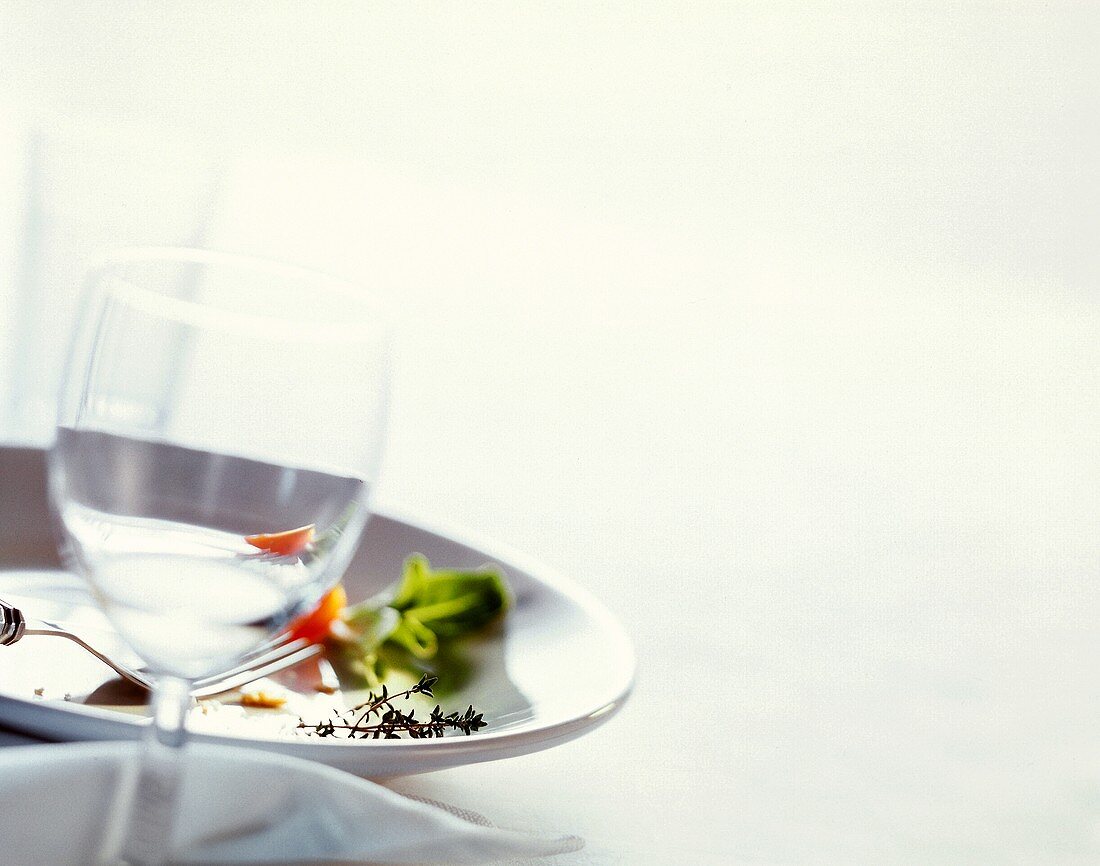 Weinglas vor einem leer gegessenen Teller