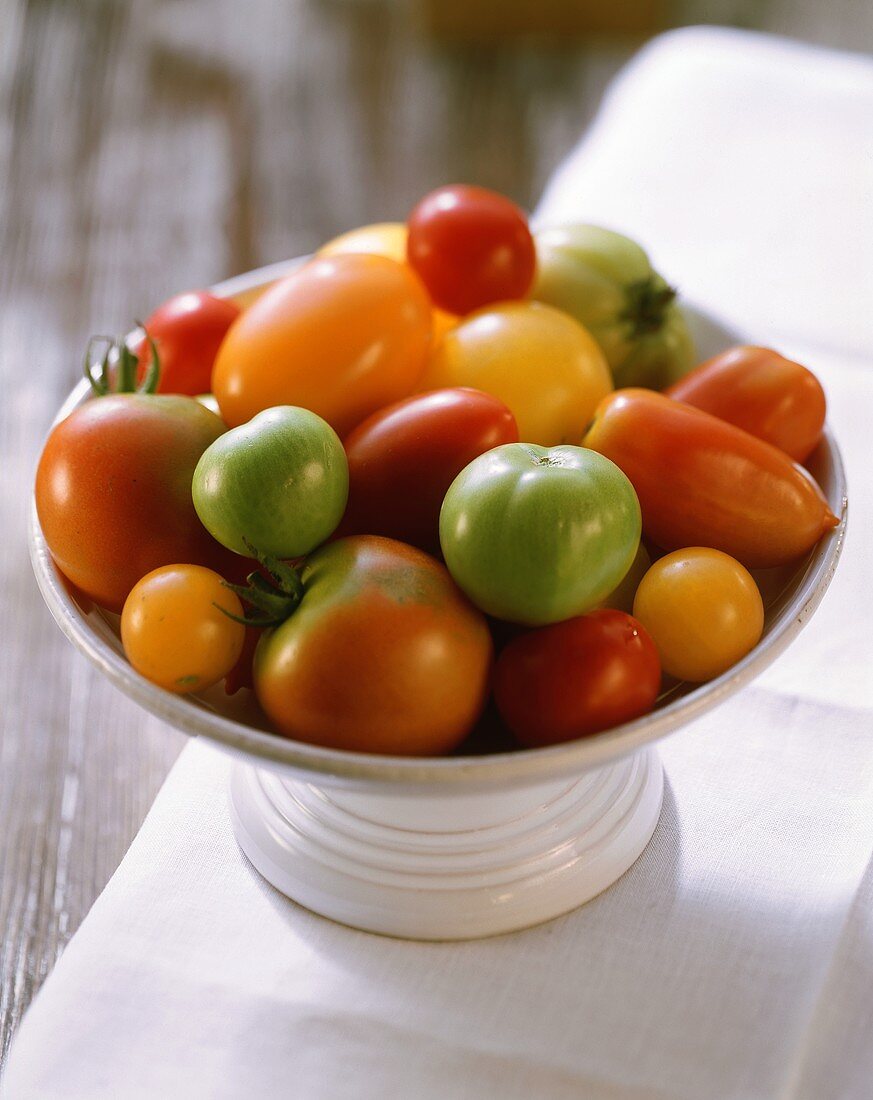 Tomatoes of various colours and sizes in a white bowl