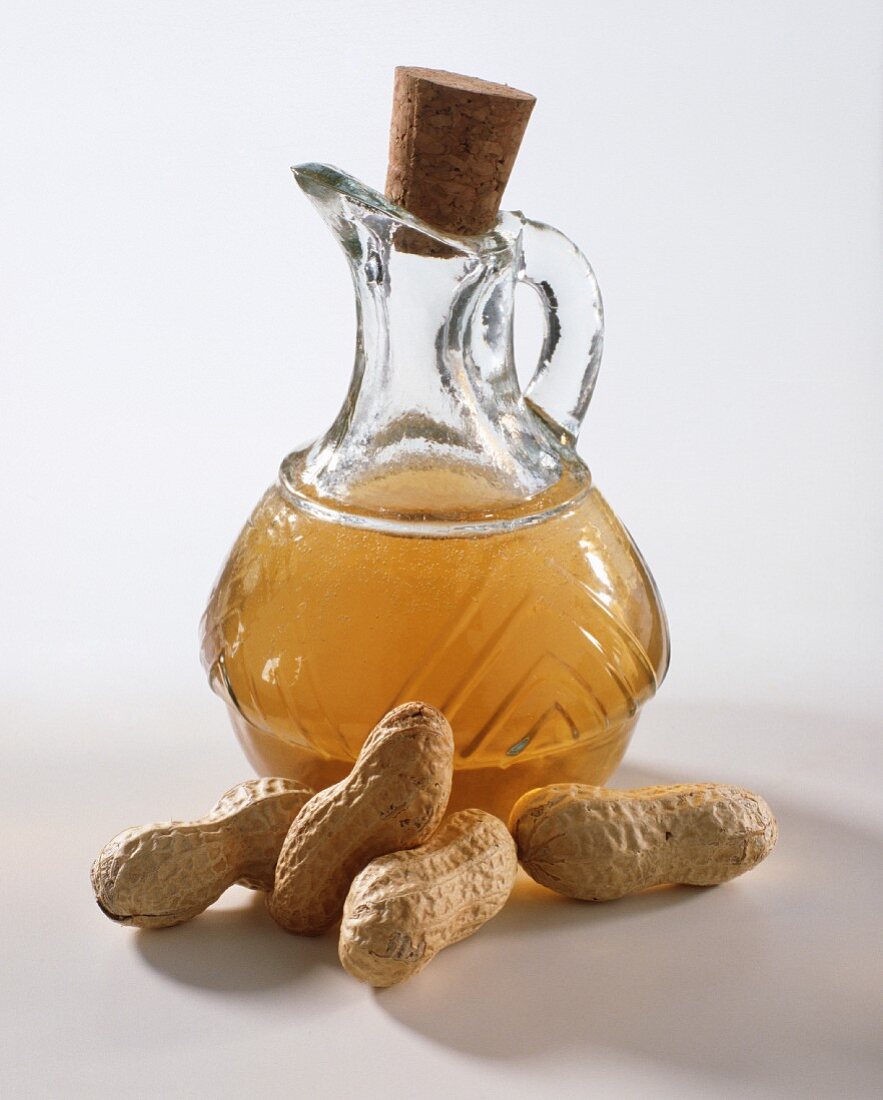 Groundnut oil in jug, peanuts in front