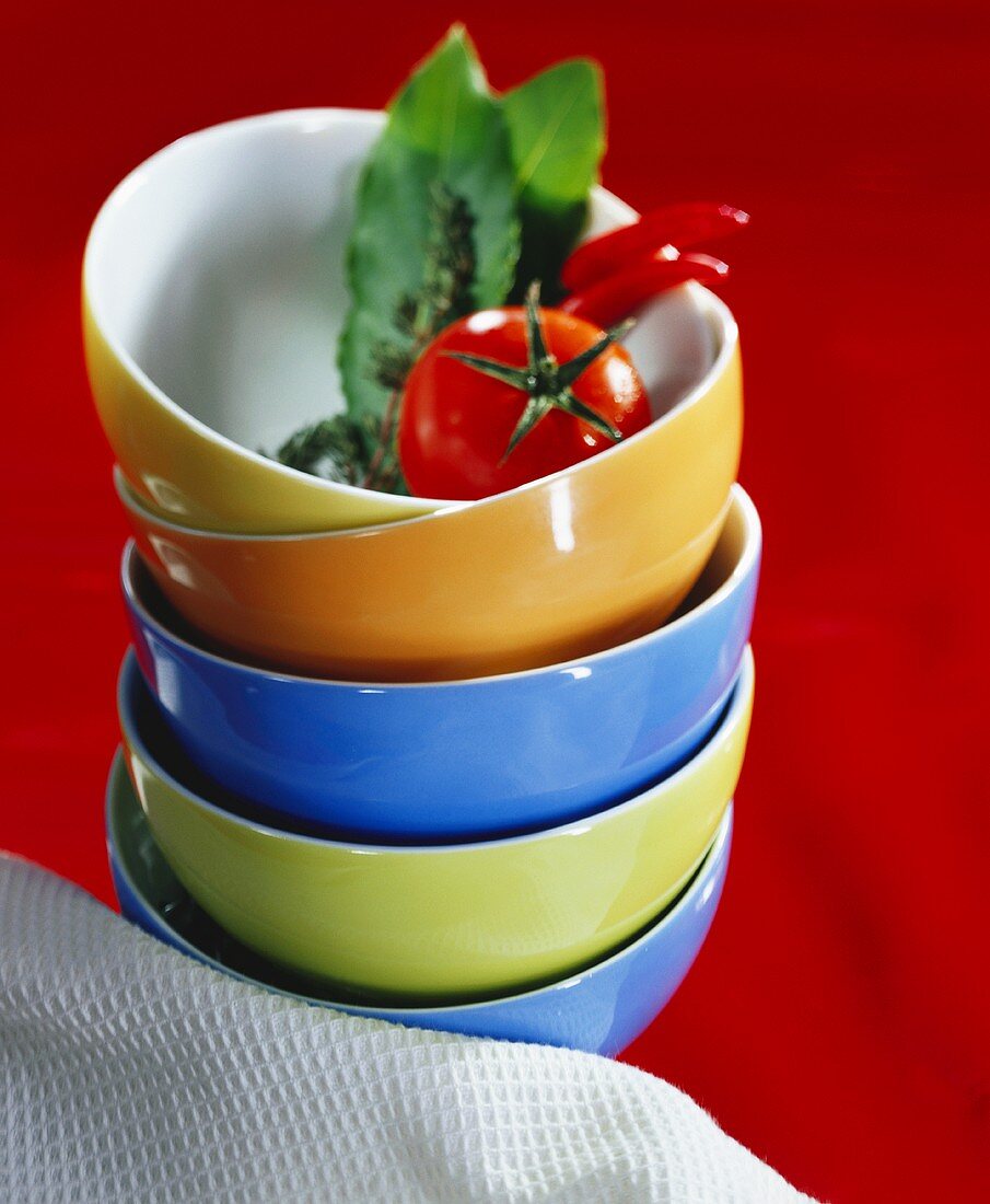 Pile of soup bowls with tomato, bay leaf and chilis