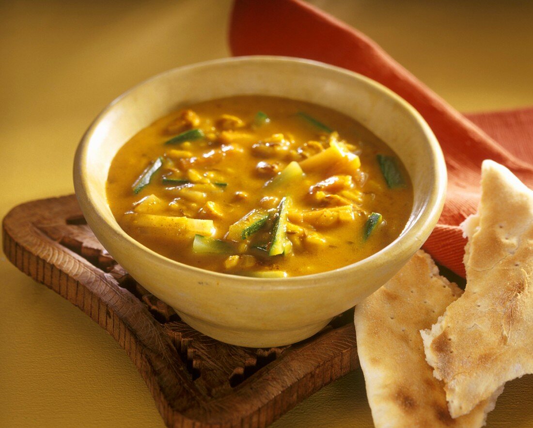 Gelbe indische Suppe mit Hähnchenbrust und Zucchninistreifen