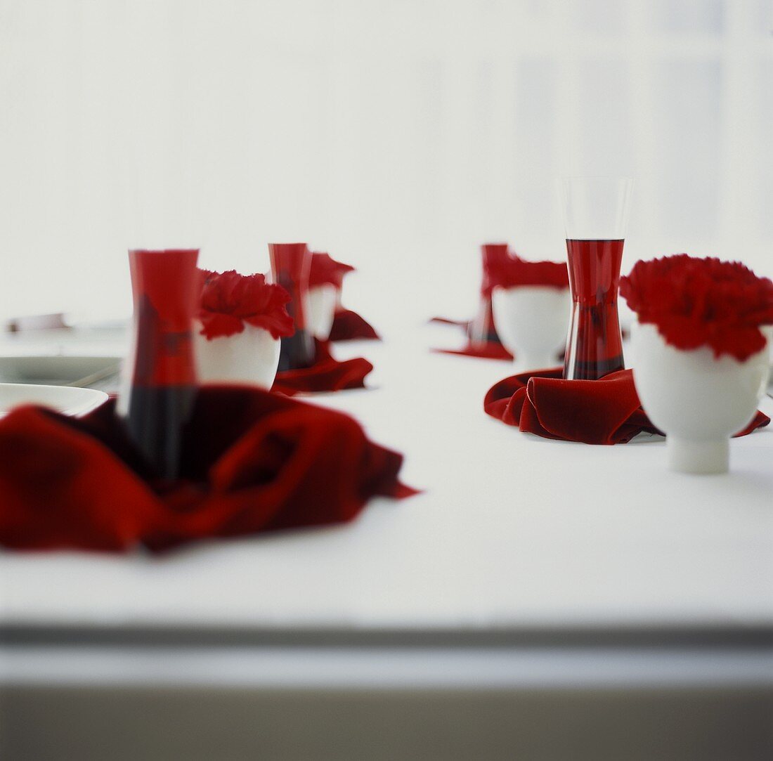 Weiß gedeckter Tisch mit Kir Royal und roten Nelken