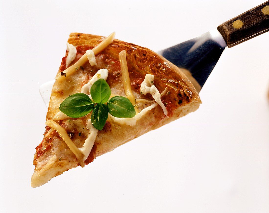 Ein Stück Pizza Margherita mit Basilikum auf Pfannenheber
