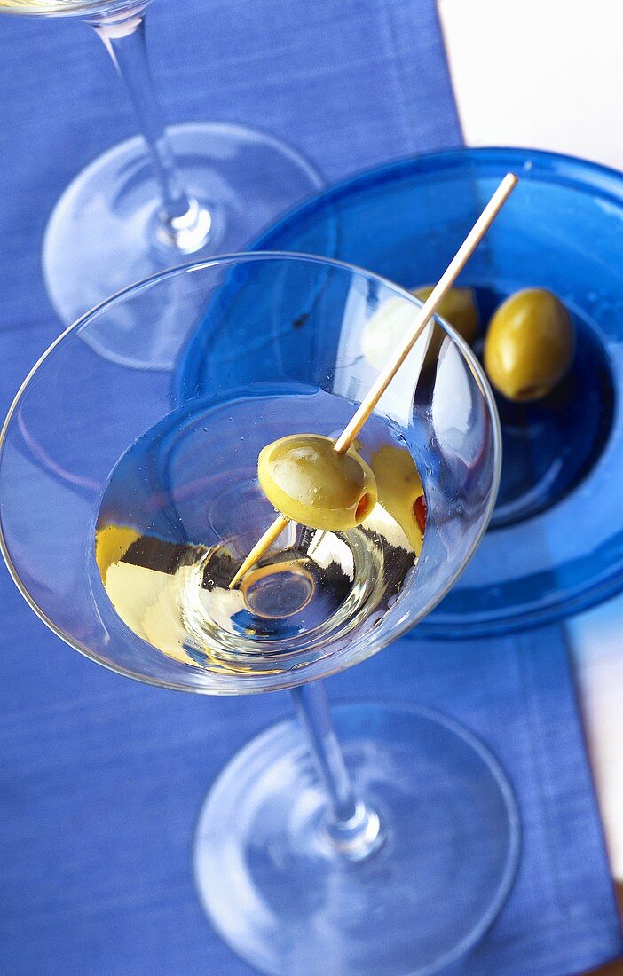 A glass of Martini cocktail with green olive